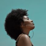 stylish dreamy black woman with afro hairstyle on blue background